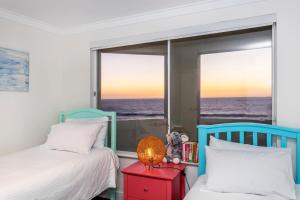 パースにあるTrigg Coastal Houseのベッドルーム1室(ベッド2台付)、海の景色を望む窓が備わります。 +15枚の写真