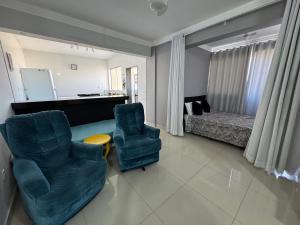 a living room with two chairs and a bed at Apartamento super central até 10 pessoas in Divinópolis