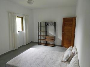 a white room with a bed and a wooden door at Casa da matta in Ubatuba