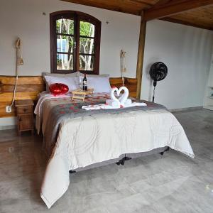 a bedroom with a bed with two swans on it at Chalé Pôr do Sol in Cunha