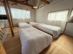 three beds in a room with wood floors and windows at 大型犬もOK!!天井高く広々空間の完全プライベート一軒家 Fully private house with high ceilings and a spacious layout even large dogs are welcome! in Yonezawa