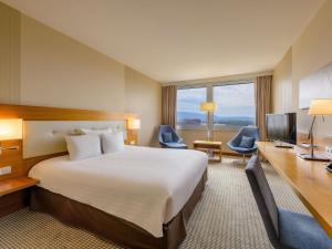 a hotel room with a large bed and a desk at Mövenpick Hotel Geneva in Geneva +202 photos
