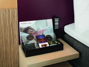a box of products sitting on a shelf next to a bed at Mövenpick Hotel Zürich-Regensdorf in Regensdorf