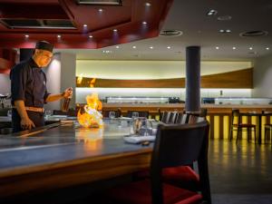 a man standing at a table in a restaurant at Mövenpick Hotel Geneva in Geneva