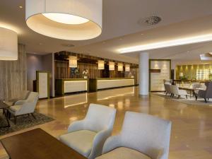 a lobby with chairs and a table in a building at Mövenpick Hotel Geneva in Geneva +180 photos