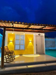 a yellow house with a chair in front of it at Hotel Alikaa Wayira in Ríohacha