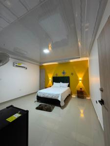 a bedroom with a bed and a yellow wall at Hotel Alikaa Wayira in Ríohacha +43 photos