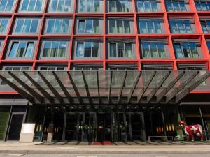 un grand bâtiment rouge avec un toit en métal dans l'établissement Mövenpick Hotel Frankfurt City Messe, à Francfort-sur-le-Main