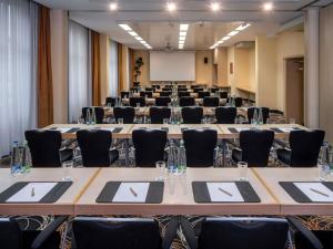 a conference room with tables and chairs and a whiteboard at Mövenpick Hotel Nürnberg Airport in Nürnberg
