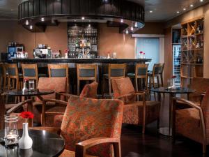 a bar in a restaurant with tables and chairs at Mövenpick Hotel Nürnberg Airport in Nürnberg