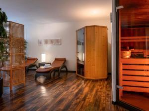a living room with a chair and a wooden cabinet at Mövenpick Hotel Nürnberg Airport in Nürnberg +108 photos