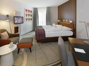 明斯特Mövenpick Hotel Münster am Aasee的一间带床和客厅的酒店房间
