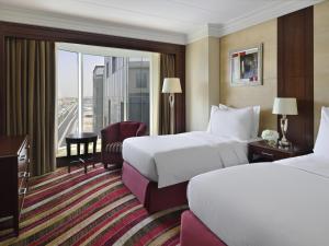 a hotel room with two beds and a balcony at Mövenpick Hotel City Star Jeddah in Jeddah