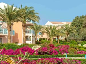a house with palm trees and flowers in a garden at Movenpick Resort & Spa El Gouna in Hurghada