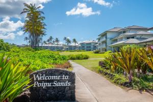 Un cartel de bienvenida a Puxtm Sands frente a un complejo turístico. en Poipu Sands by OUTRIGGER, en Koloa