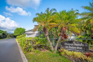 un cartel al lado de una carretera con palmeras en Poipu Sands by OUTRIGGER, en Koloa