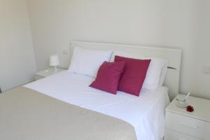 a white bed with two red pillows on it at meschihouse - Da Vinci 35 in Lecco