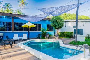 a swimming pool with a table and chairs and a blue house at Rancho Mayayi Beach house in San Miguel