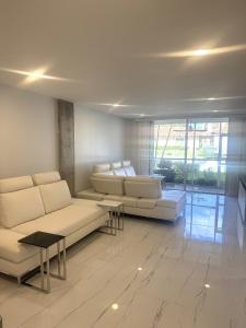 a living room with couches and tables and a large window at Contemporary Waterfront Condo in North Palm Beach