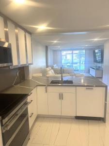 a kitchen with white cabinets and a sink at Contemporary Waterfront Condo in North Palm Beach +24 photos