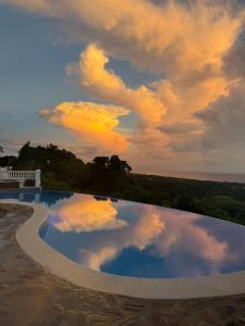 a pool with a reflection of clouds in the water at El Castillo Tropical Desconéctate de la civilización in Nagua