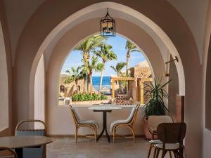 a restaurant with a view of the ocean through an archway at Movenpick Resort El Quseir in Quseir