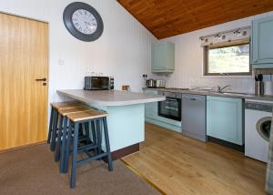 a kitchen with a counter and a clock on the wall at Lochearnhead Loch Side in Lochearnhead +20 photos