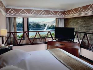 a bedroom with a large window with a bed and a television at Mövenpick Resort Aswan in Aswan