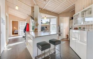 a kitchen with white cabinets and a counter with stools at Stunning Home In Tarm With Sauna in Højsand