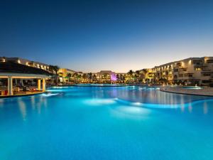 a large swimming pool with blue water at night at Movenpick Waterpark Resort & Spa Soma Bay in Hurghada