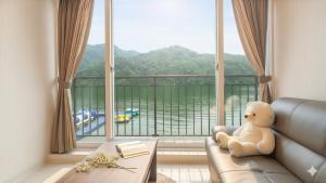 a teddy bear sitting on a couch in front of a large window at Gapyeong Rialto Pension in Gapyeong +1 photo