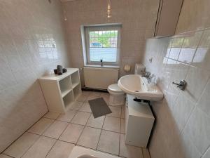 a white bathroom with a sink and a toilet at Eickhof Günter Eickhof Ferienwohnung - Ferienhof Günter in Eickhof