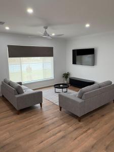 a living room with two couches and a flat screen tv at The Townhouse in Renmark
