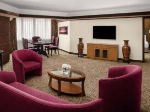 un soggiorno con mobili viola e TV di Mövenpick Hotel Karachi a Karachi