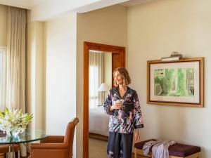 Una mujer está de pie en una habitación de hotel. en Mövenpick Hotel Doha, en Doha