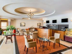 Un vestíbulo de hotel con mesas y sillas y un bar. en Mövenpick Hotel Doha, en Doha