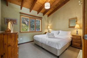 a bedroom with a white bed and a window at The Wolery - Lakeside Jindabyne in Jindabyne