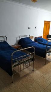 two beds with blue sheets in a room at Гостевой дом Москва in Aktobe