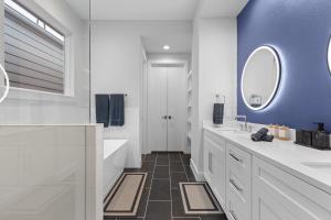 une salle de bain avec des comptoirs blancs et un mur bleu dans l'établissement Spacious Sleek Modern Art Deco Gem in Downtown HTX, à Houston 37 autres photos