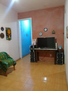 a living room with a desk with a television and a blue door at Casa em Vila Estilo Portuguesa! in Niterói