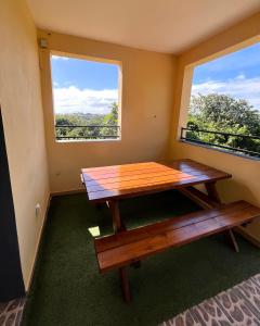a wooden table in a room with two windows at Charmant T3 en RDJ chez Ketty à Ducos in Ducos