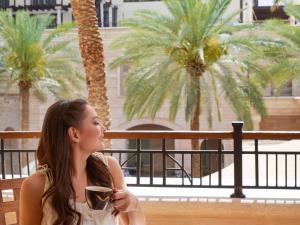 una mujer sentada en un banco sosteniendo una taza de café en Mövenpick Resort & Residences Aqaba, en Áqaba 208 fotos más