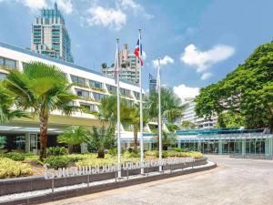 a building with palm trees in front of it at Mövenpick BDMS Wellness Resort Bangkok in Bangkok
