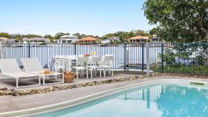 a patio with a table and chairs next to a pool at Pandanus - Spacious Waterfront Escape with Private Pontoon & Pool - Holiday Yamba in Yamba