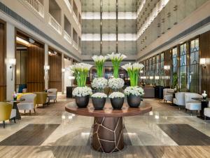 a lobby with a table with vases of flowers on it at Admiral Hotel Manila - MGallery Collection in Manila +140 photos