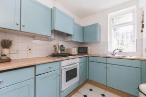 a kitchen with blue cabinets and a sink at Sleeps 5! Parking, WiFi & Parking, 4 Mins To Station, NEWLY REFURBISHED!! in London