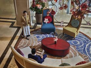 a man sitting in a chair in a lobby with a laptop at Grand Mercure Hanoi in Hanoi