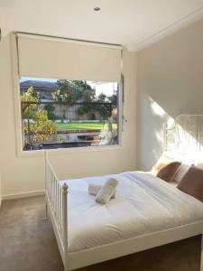 a bedroom with a white bed with a large window at Stylish 4BR Home in the Centro of Glen Waverley in Black Flat +25 photos