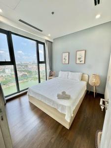 ein Schlafzimmer mit einem großen weißen Bett und großen Fenstern in der Unterkunft Vinhomes Smart City by Chill D Homestay in Phú Thú + 18 Fotos