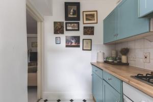 a kitchen with blue cabinets and pictures on the wall at Sleeps 5, Parking WiFi & Garden, 4 Mins To Station, NEWLY REFURBISHED! in London